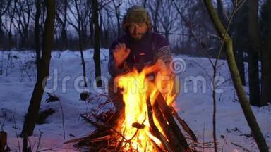 有胡子的人在冬天的炉火旁<strong>暖手</strong>。 游客晚上篝火。